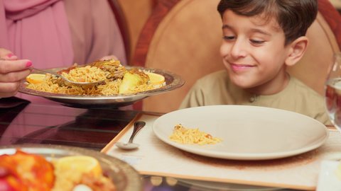 قضاء الأوقات الممتعة مع الابناء, مائدة مليئة بالاطباق والمأكولات الشعبية الشهية، أنشطة ترفيهية مسلية, الاستمتاع بالأجواء العائلية في الخارج, سيدة عربية خليجية اماراتية تقوم بإطعام ابنها في إحدى المطاعم