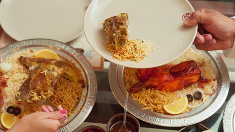 مائدة مليئة بالاطباق الشهية،  المحبة والمودة بين الزوجين, الاستمتاع بالأجواء العائلية في الخارج, قضاء الأوقات الممتعة مع الأسرة, أنشطة ترفيهية مسلية, زوجة عربية خليجية اماراتية تقوم بسكب طبق الطعام لزوجها في إحدى المطاعم