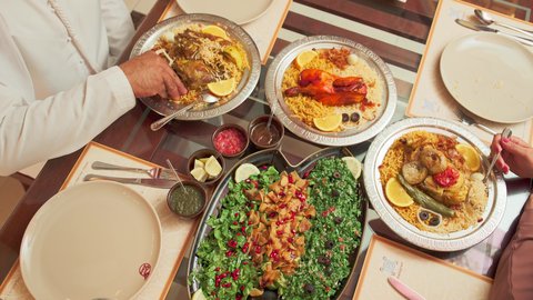 مائدة مليئة بالاطباق والمأكولات الشعبية الشهية، أنشطة ترفيهية مسلية, المحبة والمودة بين الزوجين, الاستمتاع بالأجواء العائلية في الخارج, قضاء الأوقات الممتعة مع الأسرة, زوجة عربية خليجية اماراتية تقوم بتناول الطعام مع زوجها في إحدى المطاعم