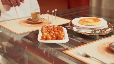 تناول الحلوى الشهية واللذيذة في احدى المطاعم، تصوير مقرب لطبق اللقيمات ذهبية اللون، حلا الزلابيات الشرقي المغموسة بالقطر، كرات العجين المقلية الصغيرة المرشوشة بالسمسم، الحلوى الشهية واللذيذة، وصفات وأطباق الحلويات والسكريات، ضيافة المناسبات والأعياد العربية