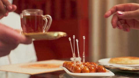 تناول الحلوى الشهية واللذيذة في احدى المطاعم، تصوير مقرب لطبق اللقيمات ذهبية اللون، حلا الزلابيات الشرقي المغموسة بالقطر، كرات العجين المقلية الصغيرة المرشوشة بالسمسم، الحلوى الشهية واللذيذة، وصفات وأطباق الحلويات والسكريات، ضيافة المناسبات والأعياد العربية