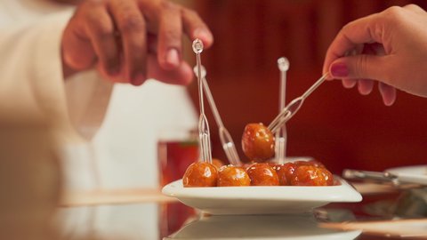 تناول الحلوى الشهية واللذيذة في احدى المطاعم، تصوير مقرب لطبق اللقيمات ذهبية اللون، حلا الزلابيات الشرقي المغموسة بالقطر، كرات العجين المقلية الصغيرة المرشوشة بالسمسم، الحلوى الشهية واللذيذة، وصفات وأطباق الحلويات والسكريات، ضيافة المناسبات والأعياد العربية