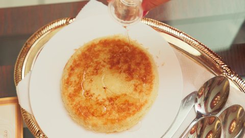 مطاعم ومأكولات في الامارات العربية المتحدة , تصوير مقرب ليد سيدة تقوم بوضع القطر على  الكنافة في المطعم , طبق من حلا الكنافة المحشوة بالقشطة والمزينة بالفستق، حلويات شرقية مشهورة، سكريات وحلويات بالقطر