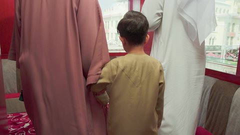 جلسات عربية تقليدية ، قضاء وقت ممتع مع الاسرة ، تصوير من الخلف لعائلة عربية خليجية اماراتية ترتدي الزي التقليدي الاماراتية تقوم بالدخول و الجلوس في احدى مطاعم الامارات ذات الاجواء الشرقية