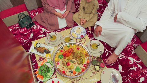 قضاء وقت ممتع مع الاسرة   ، مطاعم للمأكولات الشرقية ، فنون الطهي ووصفات طعام المطبخ الاماراتي،   منسف من الأرز الأبيض مع الدجاج المحمر والتوابل المزين بالخضراوات في احدى المطاعم الاماراتية ، عائلة عربية خليجية اماراتية تقوم بتناول اطباق شعبية شهية