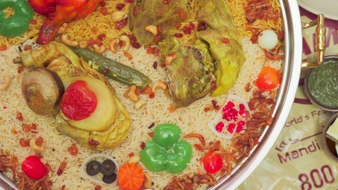 فنون الطهي ووصفات طعام المطبخ الاماراتي، مطاعم للمأكولات الشرقية الشهية، أطباق ووجبات عربية تقليدية شعبية، تصوير علوي لمنسف من الأرز الأبيض مع الدجاج المحمر والتوابل المزين بالخضراوات في احدى المطاعم الاماراتية