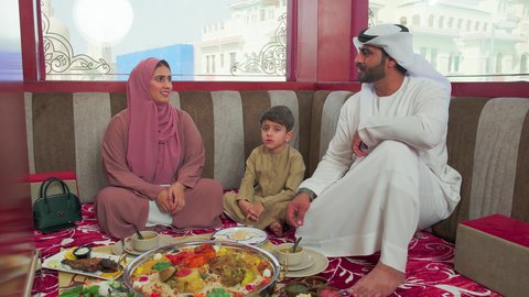قضاء وقت ممتع مع الاسرة   ، مطاعم للمأكولات الشرقية ، فنون الطهي ووصفات طعام المطبخ الاماراتي،   منسف من الأرز الأبيض مع الدجاج المحمر والتوابل المزين بالخضراوات في احدى المطاعم الاماراتية ، عائلة عربية خليجية اماراتية تقوم بتناول اطباق شعبية شهية