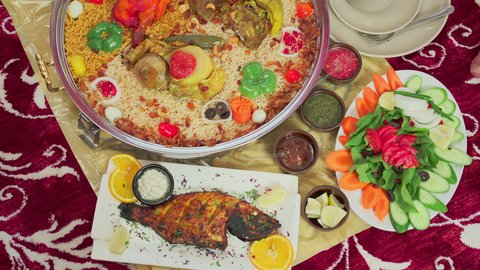 فنون الطهي ووصفات طعام المطبخ الاماراتي، مطاعم للمأكولات الشرقية الشهية، أطباق ووجبات عربية تقليدية شعبية، تصوير علوي لمنسف من الأرز الأبيض مع الدجاج المحمر والتوابل المزين بالخضراوات في احدى المطاعم الاماراتية