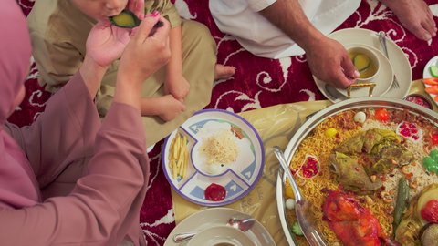 Restaurants for Eastern cuisine, traditional Arab dishes and meals, cooking arts and recipes of Emirati cuisine, an overhead shot of mansaf made with white rice, roasted chicken, and spices garnished with vegetables in one of the Emirati restaurants, a family enjoying delicious popular dishes.