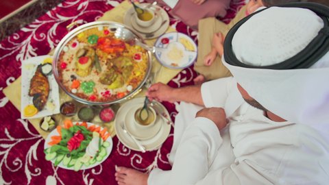 Restaurants for Eastern cuisine, traditional Arab dishes and meals, cooking arts and recipes of Emirati cuisine, an overhead shot of mansaf made with white rice, roasted chicken, and spices garnished with vegetables in one of the Emirati restaurants, a family enjoying delicious popular dishes.