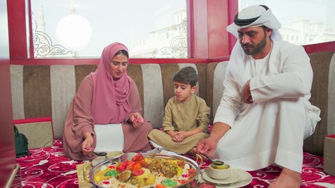 اجواء عائلية ممتعة ، مطاعم للمأكولات الشرقية ، فنون الطهي ووصفات طعام المطبخ الاماراتي،   منسف من الأرز الأبيض مع الدجاج المحمر والتوابل المزين بالخضراوات في احدى المطاعم الاماراتية ، عائلة عربية خليجية اماراتية تقوم بتناول اطباق شعبية شهية