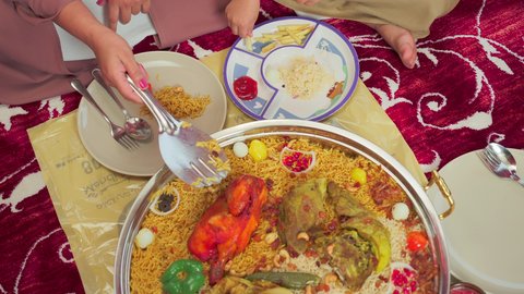 أطباق ووجبات عربية تقليدية ، فنون الطهي ووصفات طعام المطبخ الاماراتي، مطاعم للمأكولات الشرقية،  تصوير علوي لمنسف من الأرز الأبيض مع الدجاج المحمر والتوابل المزين بالخضراوات في احدى المطاعم الاماراتية ، عائلة تقوم بتناول اطباق شعبية شهية