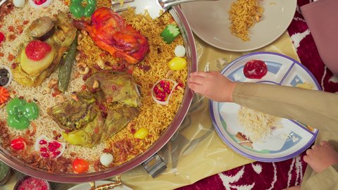 Traditional Arab dishes and meals, culinary arts and recipes of Emirati cuisine, restaurants for Eastern foods, an overhead shot of mansaf made with white rice, roasted chicken, and spices garnished with vegetables in one of the Emirati restaurants, a family enjoying delicious traditional dishes.