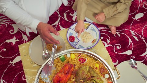 Traditional Arab dishes and meals, culinary arts and recipes of Emirati cuisine, restaurants for Eastern foods, an overhead shot of mansaf made with white rice, roasted chicken, and spices garnished with vegetables in one of the Emirati restaurants, a family enjoying delicious traditional dishes.