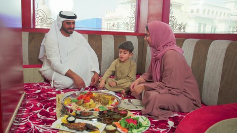 قضاء وقت ممتع مع الابناء ، مطاعم للمأكولات الشرقية ، فنون الطهي ووصفات طعام المطبخ الاماراتي،   منسف من الأرز الأبيض مع الدجاج المحمر والتوابل المزين بالخضراوات في احدى المطاعم الاماراتية ، عائلة عربية خليجية اماراتية تقوم بتناول اطباق شعبية شهية