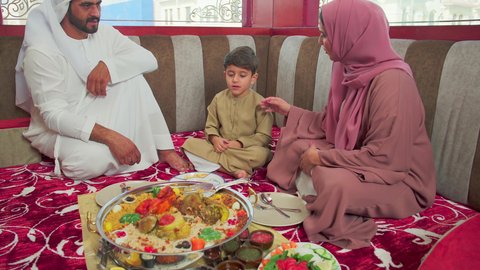 اجواء عائلية ممتعة ، مطاعم للمأكولات الشرقية ، فنون الطهي ووصفات طعام المطبخ الاماراتي،   منسف من الأرز الأبيض مع الدجاج المحمر والتوابل المزين بالخضراوات في احدى المطاعم الاماراتية ، عائلة عربية خليجية اماراتية تقوم بتناول اطباق شعبية شهية