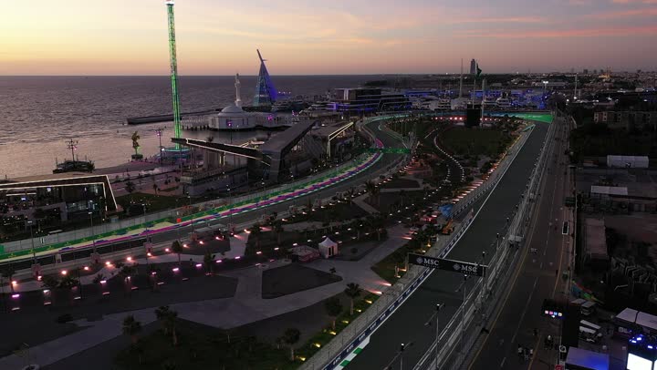 مضمار سباقات للفورمولا 1، نشاط رياضي ترفيهي شبابي، رياضة السيارات على سواحل البحر الأحمر، تصوير درون لمسار حلبة وقت غروب الشمس في كورنيش جدة في المملكة العربية السعودية، اماكن ومعالم سياحة، لعبة الدولاب الكهربائي الملون