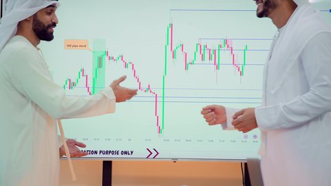 مصافحة وسلام بين الاشخاص، عقد صفقات جديدة ، دمج الأجهزة التقنية الحديثة بالأعمال المكتبية، تطوير المشاريع و الاستثمارات، إدارة و تقسيم المهام، شرح و تحليل الرسوم البيانية, فريق عمل عربي خليجي اماراتي يقوم بإجراء اجتماع عمل داخل غرفة الاجتماعات في مقر الشركة