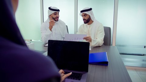 المناقشة في أداء المهام واكتساب الخبرة، دمج الأجهزة التقنية الحديثة بالأعمال المكتبية، تطوير المشاريع و الاستثمارات، إدارة و تقسيم المهام، شرح و تحليل الرسوم البيانية, فريق عمل عربي خليجي اماراتي يقوم بإجراء اجتماع عمل داخل غرفة الاجتماعات في مقر الشركة