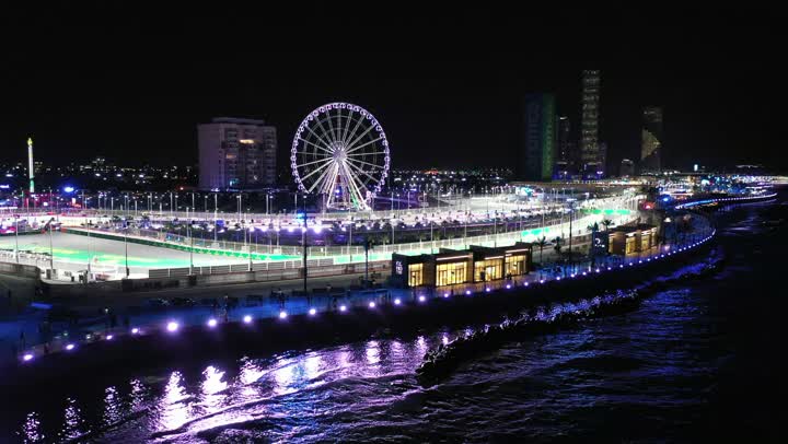 منظر الدولاب الكهربائي واحدة من الألعاب الترفيهية، رياضة السيارات على سواحل البحر الأحمر،تصوير درون لمسار حلبة كورنيش جدة في المملكة العربية السعودية المضاءة في وقت الليل، مضمار سباقات للفورمولا 1، اماكن ومعالم سياحة، نشاط رياضي ترفيهي شبابي