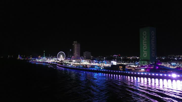نشاط رياضي ترفيهي شبابي، رياضة السيارات على سواحل البحر الأحمر،تصوير درون لمسار حلبة كورنيش جدة في المملكة العربية السعودية المضاءة في وقت الليل، مضمار سباقات للفورمولا 1، اماكن ومعالم سياحة، الفن الهندسي المتطور للأبراج وناطحات السحاب