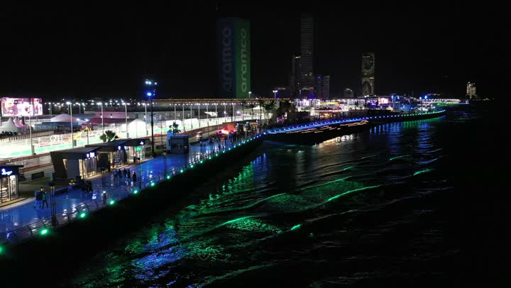 الأمواج المتلاطمة في البحر الأحمر، اماكن ومعالم سياحة، الفن الهندسي المتطور للأبراج وناطحات السحاب، نشاط رياضي ترفيهي شبابي، رياضة السيارات على ساحل جدة، تصوير درون لمسار حلبة كورنيش جدة في المملكة العربية السعودية المضاءة في وقت الليل، مضمار سباقات للفورمولا 1