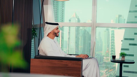 مفهوم الطاقة والإيجابية، قضاء وقت ممتع و هادئ، الحيوية والنشاط عند شرب الكافيين، رجل عربي خليجي اماراتي يرتدي الكندورة و الغتره يجلس على كرسي بجانب النافذة يحمل بيده فنجان من القهوه، الاستمتاع بتناول المشروبات الساخن، احتساء المشروب المفضل