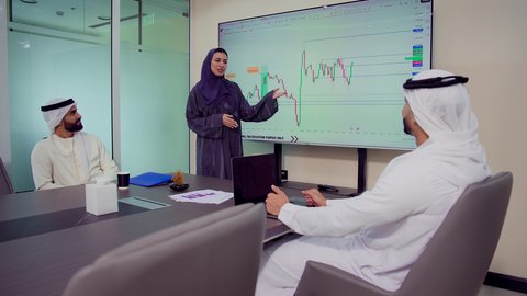 مهن ووظائف نسائية، ايماءات الثقة بالنفس والسرور، دمج الأجهزة التقنية الحديثة بالأعمال المكتبية، تطوير المشاريع و الاستثمارات، إدارة و تقسيم المهام، شرح و تحليل الرسوم البيانية, فريق عمل عربي خليجي اماراتي يقوم بإجراء اجتماع عمل داخل غرفة الاجتماعات في مقر الشركة