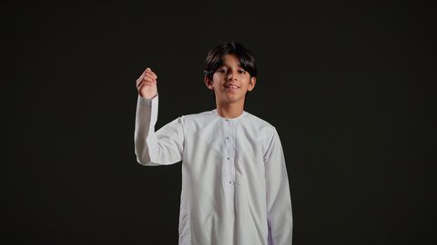 الإمتياز والتميز والنجاح، بورتريه لولد عربي خليجي سعودي يرتدي الثوب الابيض يرفع أصابع الإبهام لأعلى، إيماءات السعادة والإعجاب والموافقة، حركة أصبع تدل على القبول والرضا، خلفية سوداء