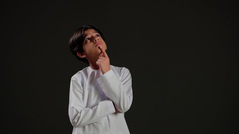 التفكير والتخطيط لشيء ما، ايماءات وجه تدل على التمعن والتدقيق، بورتريه لولد عربي خليجي سعودي يرتدي الثوب الابيض ينظر للافق بعمق، مفهوم النظرة المستقبلية، خلفية سوداء