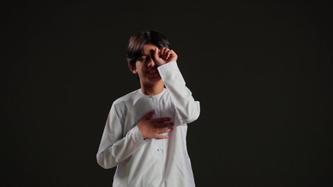 الإحساس بالإرهاق و الحاجه الى النوم والراحه ,بورتريه لولد عربي خليجي سعودي يرتدي الثوب الابيض يقوم بفرك عينه، إيماءات تدل على النعاس, الشعور بالتعب والكسل والخمول، خلفية سوداء