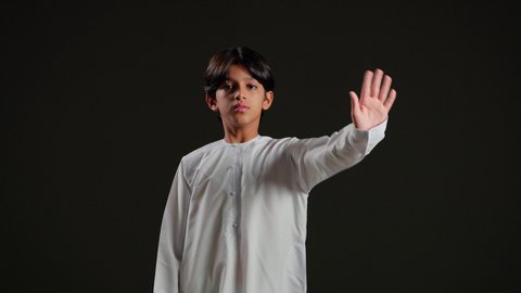 الأمر بالتوقف عن فعل شيء ما، تعابير الرفض والإمتناع، بورتريه لولد عربي خليجي سعودي يرتدي الثوب الابيض يرفع يده بإيماءات النهي، الشعور بالإنزعاج والغضب، خلفيه سوداء