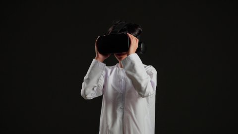 النظر الى الافلام الواقعيه، التسلية والمتعة بالمشاهدة عبر نظارة الواقع الافتراضي، استخدام التقنيات والأجهزة المتطورة، محاكاة العالم الخيالي ، بورتريه لولد عربي خليجي سعودي يرتدي الثوب الابيض ينظر من خلال نظارات ثلاثية الأبعاد (الفي ار), خلفية سوداء