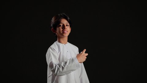 مفهوم التعطر والتطيب، عطورات خليجية سعودية, الاهتمام بالمظهر الخارجي, استخدام الزيوت العطرية الطبيعية, بورتريه لولد عربي خليجي سعودي يرتديالثوب الابيض يحمل زجاجة العطر, خلفية سوداء