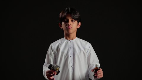 إستخدام الدواء بوصفة طبية، بورتريه مقرب لولد عربي خليجي سعودي يرتدي الثوب الابيض يحمل بيده مجموعة من علب الدواء  ، علاج الأمراض, مفهوم الصيدلة ، خلفية سوداء