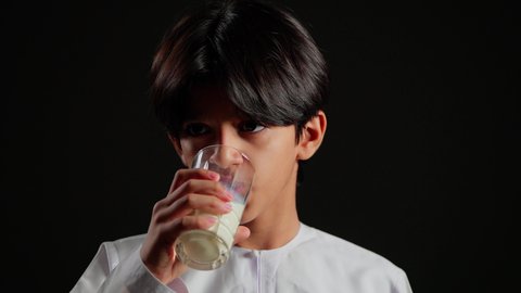 فوائد مشتقات اللبن المتعددة للجسم والعظام، اتباع نظام غذائي صحي, بورتريه مقرب لولد عربي خليجي سعودي يرتدي الثوب الابيض يقوم بشرب كأس من الحليب، المحافظة على سلامة الجهاز المناعي، مفهوم العناية والاهتمام بالصحة, خلفية سوداء