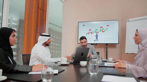 متابعة مخطط الرسم البياني، استخدام التكنوجيا والتقنيات الحديثة  ، مراجعة تقارير العمل ،دراسة مشاريع جديدة، مفهوم النمو الاقتصادي والاستثمار المالي،  اصدقاء عمل عربيون خليجيون اماراتيون يقومون بتحليل البيانات على الحاسوب المحمول