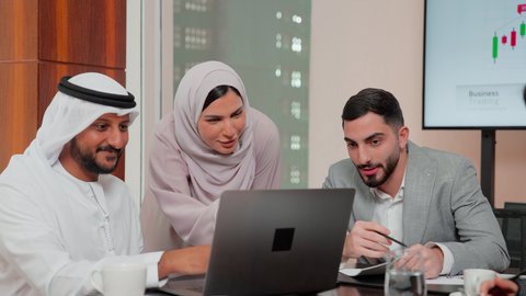 متابعة مخطط الرسم البياني، استخدام التكنوجيا والتقنيات الحديثة  ، مراجعة تقارير العمل ،دراسة مشاريع جديدة، مفهوم النمو الاقتصادي والاستثمار المالي،  اصدقاء عمل عربيون خليجيون اماراتيون يقومون بتحليل البيانات على الحاسوب المحمول