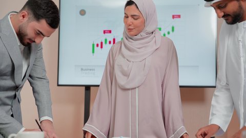 Following a chart, using technology and modern techniques, reviewing work reports, studying new projects, the concept of economic growth and financial investment, Arab Gulf and Emirati business friends analyzing data on a laptop