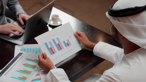 استخدام التكنولوجيا والتقنيات الحديثة فى العمل ،تدقيق وتحليل بيانات المشروع،دراسة مشاريع جديدة، مجموعة من اصدقاء عمل عربيان خليجيان اماراتيان يقومان بتحليل البيانات على الحاسوب المحمول، متابعة مخطط الرسم البياني، مفهوم النمو الاقتصادي والاستثمار المالي