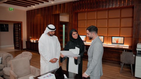 Unity and teamwork, the concept of economic growth and financial investment, studying new projects, following the flowchart, using technology and modern techniques, reviewing work reports, Arab Gulf and Emirati work friends analyzing data on a laptop