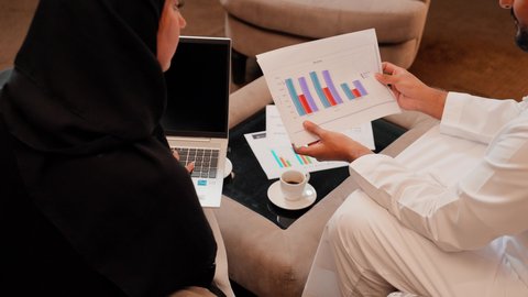 مفهوم النمو الاقتصادي والاستثمار المالي، زميلان عمل عربيان خليجيان اماراتيان يقومان بتحليل البيانات على الحاسوب المحمول، متابعة مخطط الرسم البياني، تدقيق وتحليل بيانات المشروع، دراسة مشاريع جديدة، مفهوم النمو الاقتصادي والاستثمار المالي