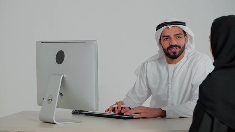 بيئة العمل المريحة في الشركات الراقية, البشاشة وحسن الاستقبال, الحوار والنقاش وتقديم الخدمات للعملاء, تصوير مقرب لرجل عربي خليجي اماراتي يرتدي الكندورة و الغتره  يقوم بالرد على الاستفسار في مكتب الخدمة, مهن ووظائف اماراتية، كتابة و تسجيل الملاحظات