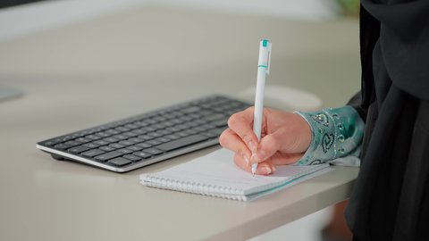 استخدام الورق الأبيض في تسجيل الملاحظات والمعلومات المهمة، مفهوم كتابه وتدوين الملاحظات، تصوير مقرب ليد امراة عربية خليجية سعودية تمسك بيدها قلم تقوم بالكتابة على نوت