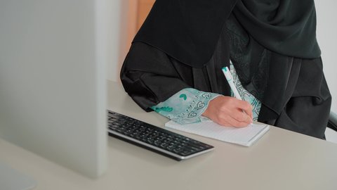 مفهوم كتابه وتدوين الملاحظات، استخدام الورق الأبيض في تسجيل الملاحظات والمعلومات المهمة، تصوير مقرب ليد امراة عربية خليجية سعودية تمسك بيدها قلم تقوم بالكتابة على نوت