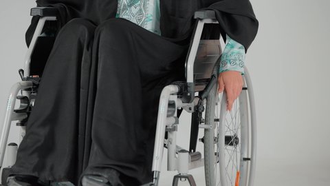 تحسين حياة ذوي الاعاقه الحركيه للمساعده على التنقل، الحفاظ على الصحة البدنية من خلال تحريك اليدين أثناء الحركة, تصوير مقرب ليد سيده عربيه خليجيه سعوديه ترتدي العباءه السوداء تجلس على كرسي متحرك من ذوي أصحاب الهمم تقوم بتحريكه بنفسها