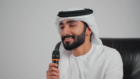 الدورات التدريبية و ورشات العمل، إلقاء المحاضرات وإقامة الندوات، تسجيل المقاطع الصوتية والغنائية، تصوير مقرب  لرجل عربي خليجي اماراتي يرتدي الكندورة و الغتره يجلس على كرسي يحمل بيده مكبر الصوت