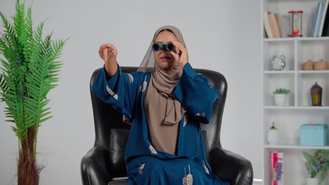 رؤية الاشياء البعيدة عبر التلسكوب، التخطيط المستقبلي للأهداف و الطموحات، حب الاستكشاف والمغامرة، امرأة عربية خليجية سعودية ترتدي العباءة والحجاب تجلس على كرسي تنظر من خلال منظار ثنائي العينين، الاشارة الى شيء ما
