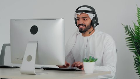 النقرعلى لوحه المفاتيح، استخدام الهيدفون والتقنيات المتطورة في العمل، التواصل مع الزبائن لحل المشكلات والشكاوي، الاجابه على اسئلة العملاء، موظف عربي خليجي سعودي يضع سماعة الرأس الصوتية يجلس امام الحاسب الالى يعمل في مجال خدمة العملاء ، اجراء اتصال من خلال جهاز الحاسوب