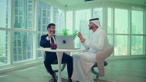 مناقشة بيانات المشروع، متابعة مخطط الرسم البياني،  النمو الاقتصادي والاستثمار المالي ، دراسة مشاريع جديدة،صعود وهبوط البورصة، اجتماع زملاء عمل فى مقر عملهم احدهما يرتدي البدلة الرسمية يقومون بتحليل البيانات على الحاسوب المحمول